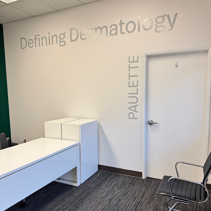 Dermatology office interior with a desk, chair, and wall text.