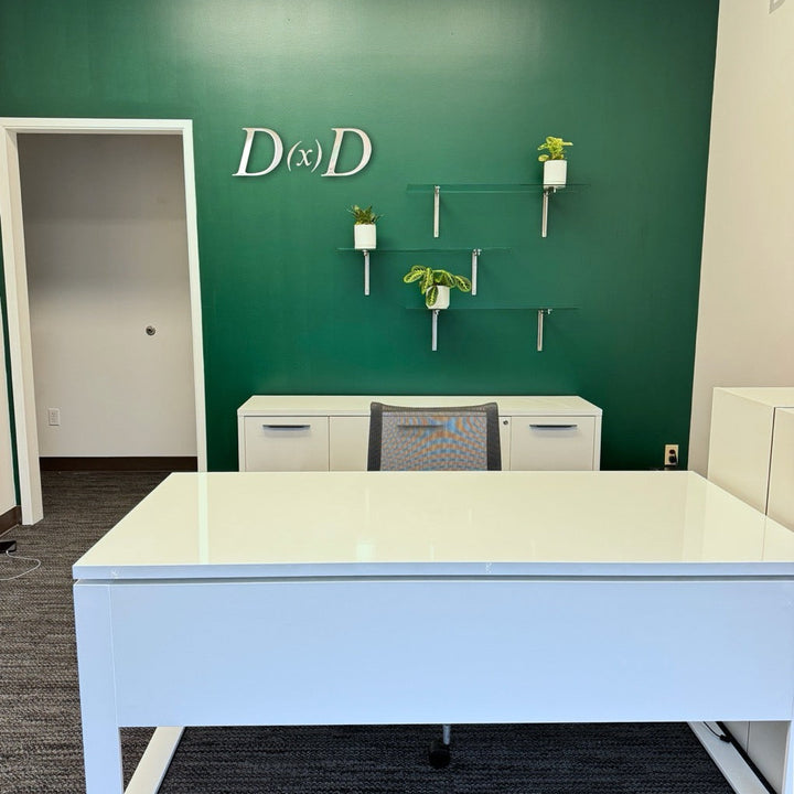 Modern office setup with a desk in front of a green wall featuring the letters 'D' and 'D'.